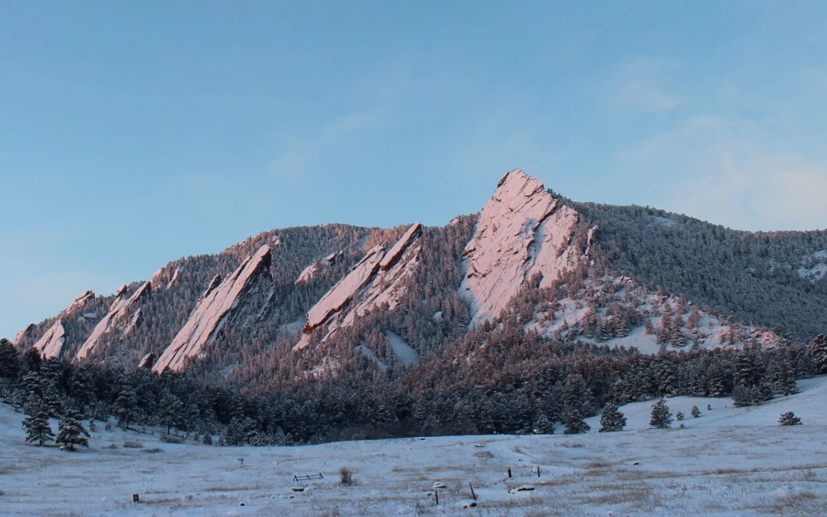 The flat irons at sunrise with a fresh dusting on snow. The flatirons are pink from the soft sunlight.