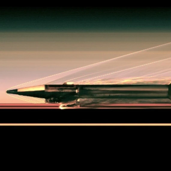 Close-up view of a hypersonic test sled racing along a test track, showing detailed structural components and heat-resistant materials as it moves at extreme speed, with shockwaves visible.